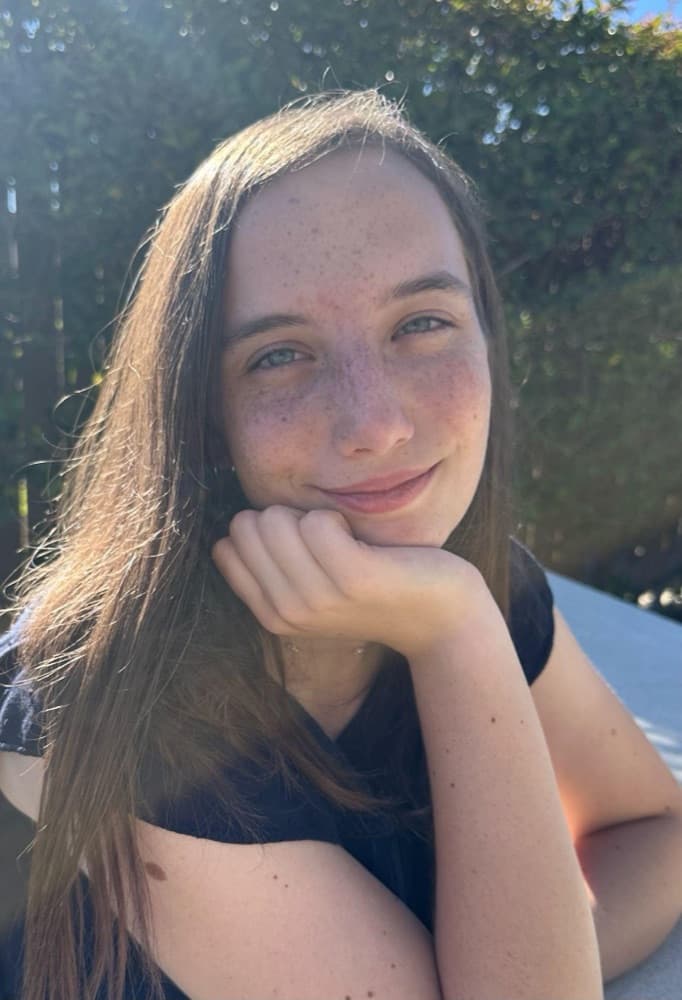 Bobbie Lathrop smiling outdoors, chin resting on one hand